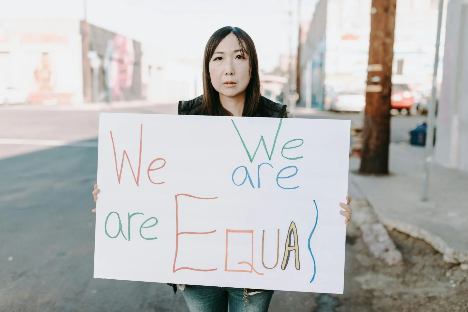 Asian woman holding paper with ''we are all equal''