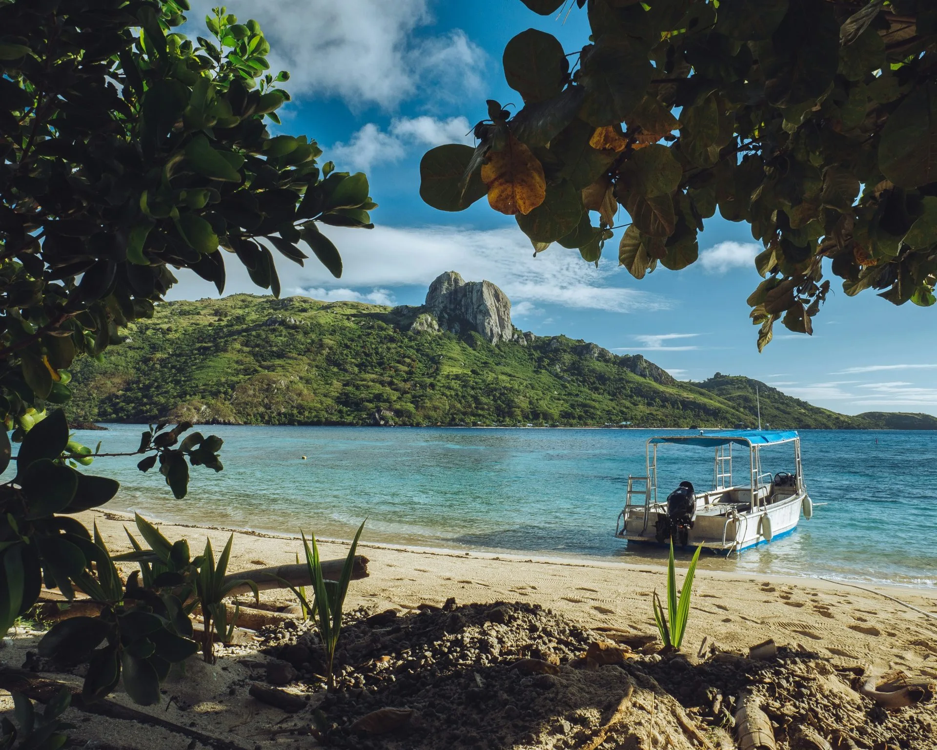 Island beach with mountains in the background and a fisher's boat at the beach