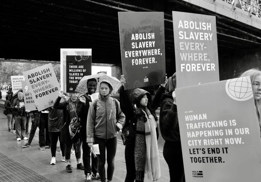 People walking with signs reading Abolish Slavery Everywhere, Forever and Human Trafficking Is Happening in Our City Right Now.